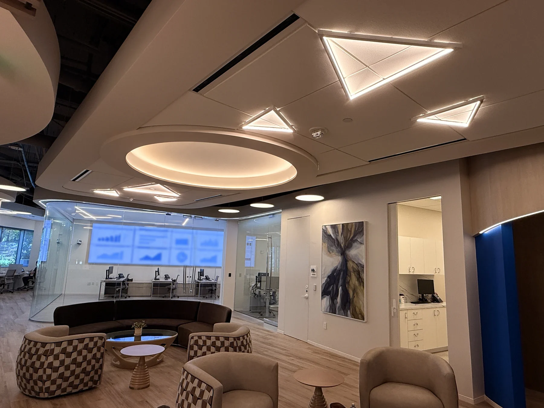 Shared seating beneath a circular cove ceiling, with the glass-enclosed command center beyond.