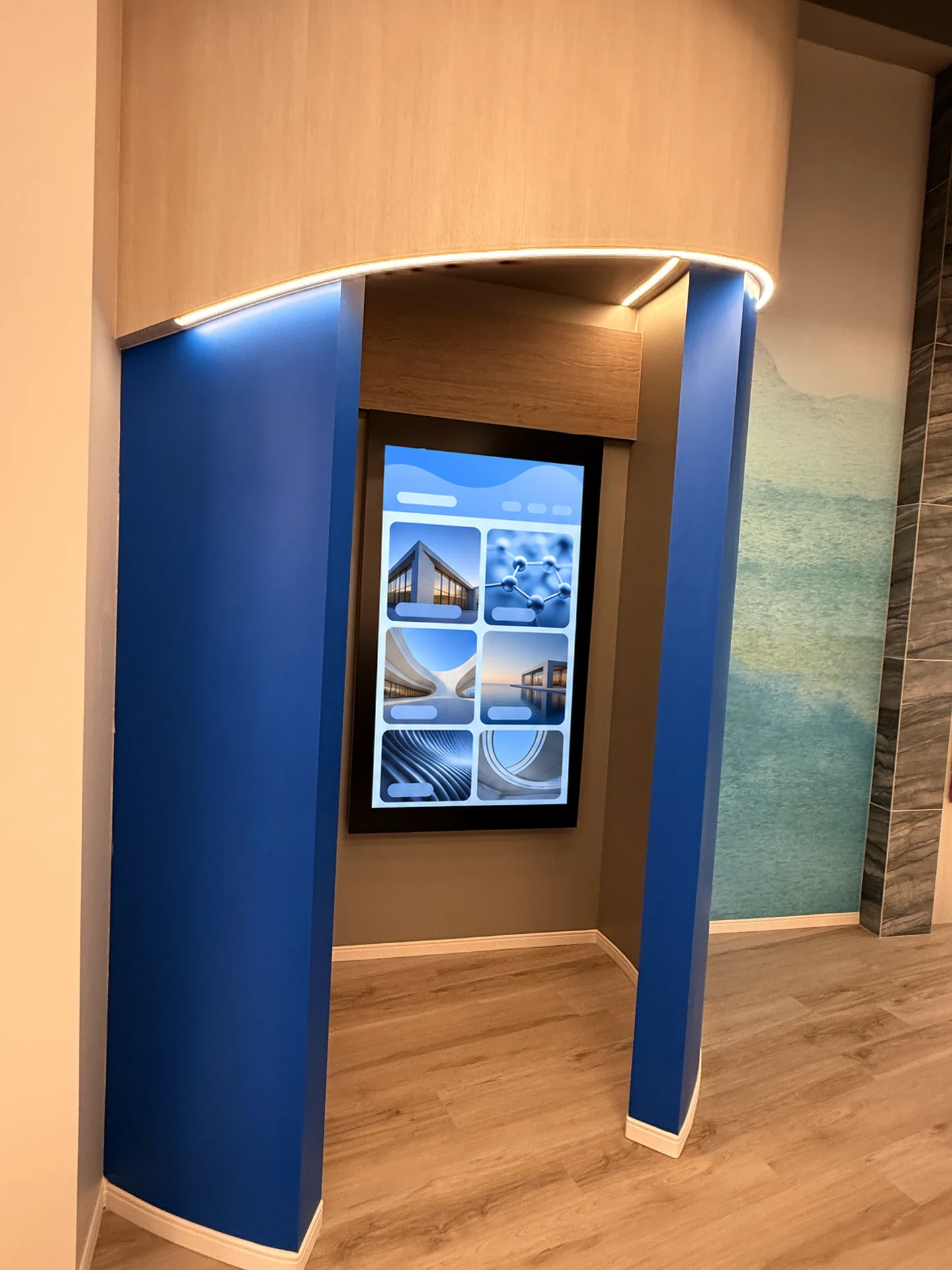 The installed portrait touchscreen in the patient-story area, set into a blue architectural surround.