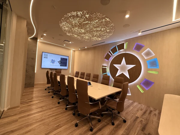 Wide view of the conference room with a large wall display and illuminated Texas Cancer Interception Institute emblem.