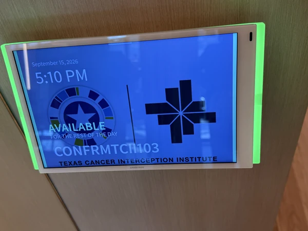 Conference-room scheduling panel with green availability lighting.